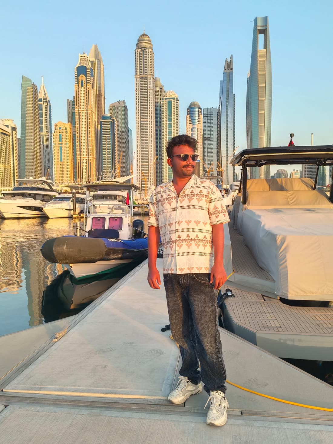 Harshad standing on a Dubai Marina pier with yachts and the skyline behind him